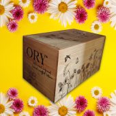 ORY wooden gift box with engraved logo and floral illustration, displayed on a vibrant yellow background framed by daisies and pink flowers, highlighting personalized botanical skincare gifting.