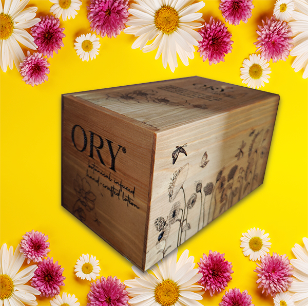 ORY Wooden Gift Box with Custom Engraving | Botanical Skincare Gift Packaging ORY wooden gift box with engraved logo and floral illustration, displayed on a vibrant yellow background framed by daisies and pink flowers, highlighting personalized botanical skincare gifting.
