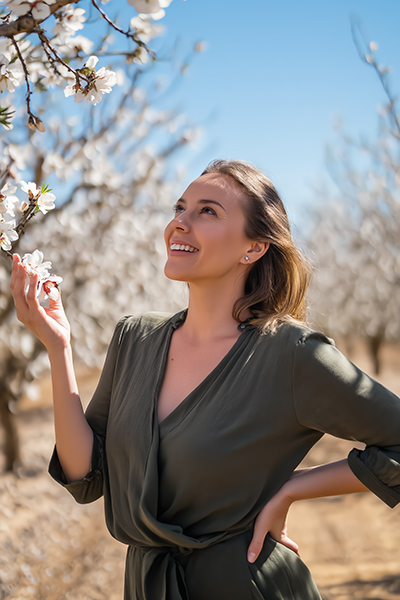 Sweet Almond Oil – Gentle Nourishment & Lasting Softness Woman in a blooming almond orchard with radiant, nourished skin, symbolizing the gentle moisturizing and soothing benefits of sweet almond oil in skincare.