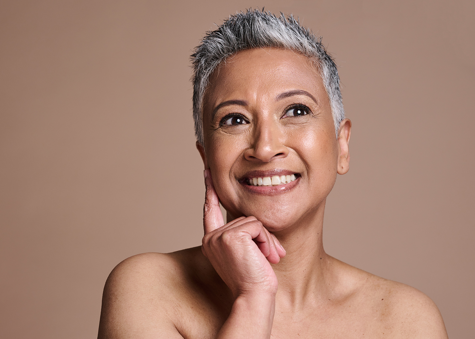 woman-mature-skin-9 Smiling mature woman with radiant, healthy skin touching her face — ORY Skincare mature skincare for hydration, firmness, and radiance.